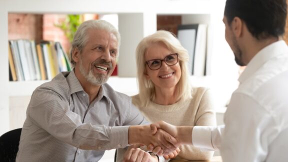 senior couple shaking hands with insurance salesman. By Fizkes. Case study on Medicare lead generation